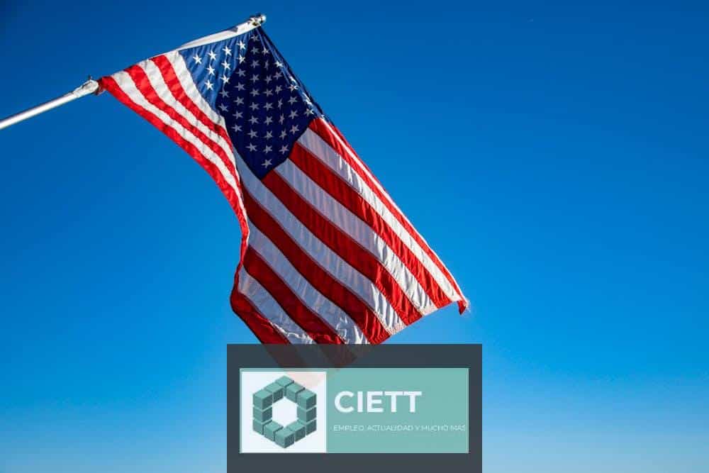 The American flag proudly waves on a flagpole against a clear blue sky, symbolizing freedom and patriotism.